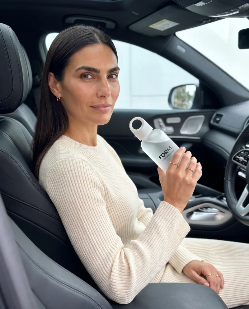 A model holding the FORM. bottle in a car