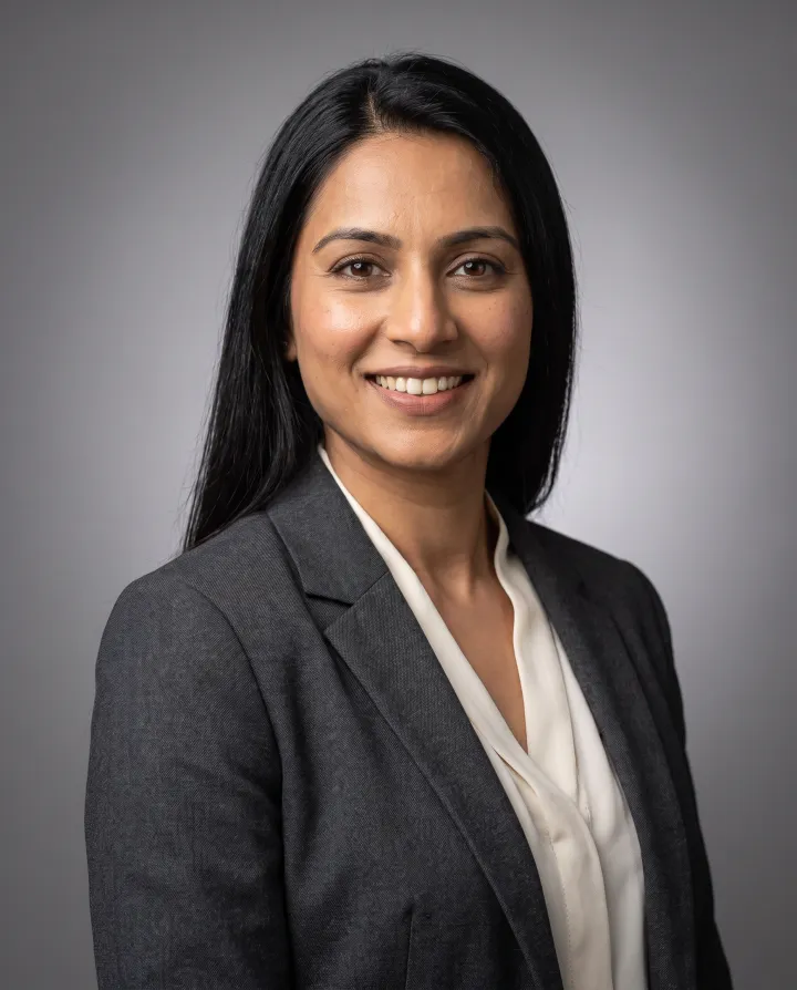 A studio headshot of a woman in a charcoal blazer